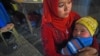 Уйгурка держит своего ребенка на ночном рынке в Хотане в западном регионе Китая Синьцзян. 