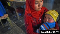 A Uyghur woman holds her baby at a market in Hotan in China's western Xinjiang region. (file photo)