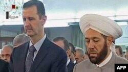 Сирия президенті Башар Асад (сол жақта) елдің бас мүфтиі Ахмед Хассунмен бірге намаз оқып тұр. Дамаск, 8 тамыз 2013 жыл. 
