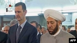 A TV screenshot apparently shows Syrian President Bashar al-Assad (left) attending morning prayers in Damascus on August 8.