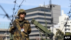 Боец Сил самообороны Японии на фоне усовершенствованного ЗРК «Пэтриот» PAC-3 американского производства