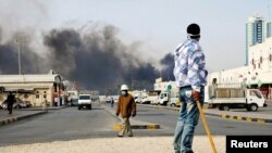 Bahrain -- An anti-government protester stands holding a stick as Gulf Cooperation Council forces move in to evacuate Pearl Square in Manama, 16Mar2011