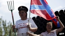 A woman rides on the back of a truck holding a pitchfork and a flag of Novorossia (Newrussia, a union between the "Donetsk People's Republic and "Lugansk People's Republic") in the parade on August 24 in Donetsk.