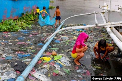 Дети в трущобах Манилы, столицы Филиппин, ловят маленьких рыбок для еды. Осень 2020 года