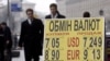 Ukrainians pass by an exchange-rate board in downtown Kyiv.