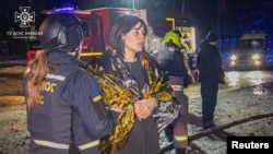 Salvatorii asistă o femeie în urma unui atac cu rachete rusești asupra unui hotel din Harkov în seara zilei de 10 ianuarie.