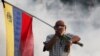 An opponent of President Nicolas Maduro carrying a Venezuelan flag covers his face amid tear gas fired by soldiers loyal to Maduro during an attempted military uprising to oust Maduro in Caracas on April 30.