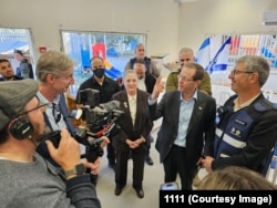 Israeli President Isaac Herzog (second right) speaks to RFE/RL's Ray Furlong (second left) while visiting a kindergarten in Ramla on March 12 that had been hit by an Iranian missile three days earlier.
