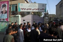 People gather at the site of a deadly suicide bombing that targeted a training class in the Shi'ite neighborhood of Dasht-e Barcha on August 15.