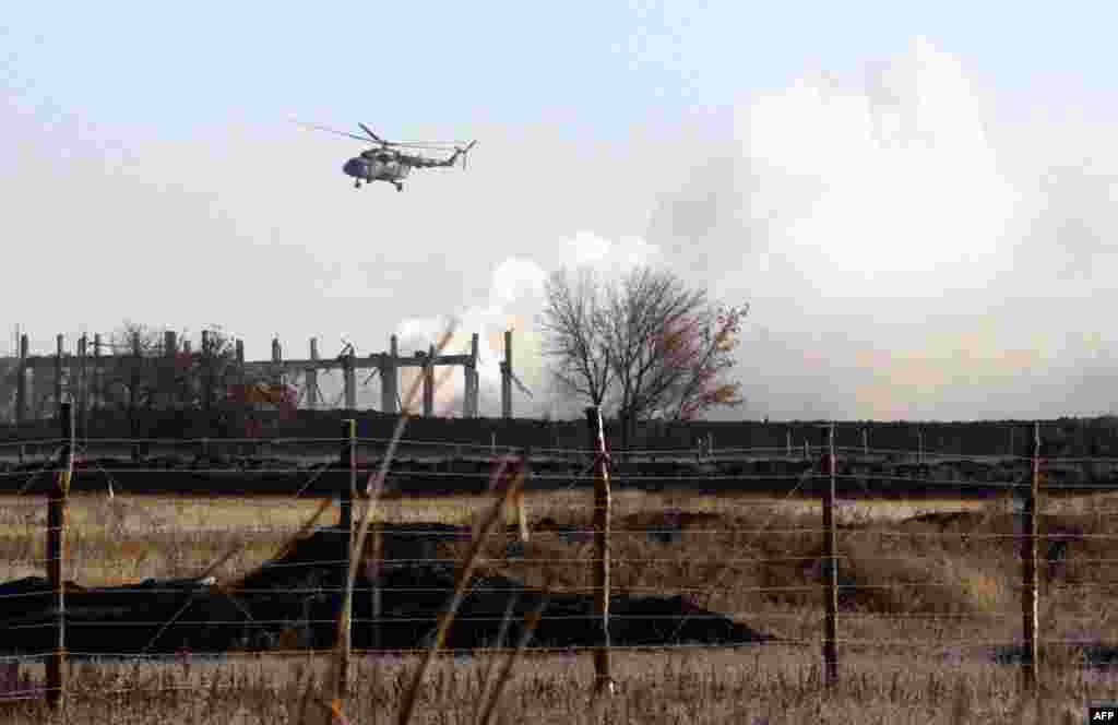 Військовий вертоліт пролітає над палаючими складами
