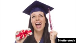 Shutterstock. Happy Female Graduate in Cap and Gown Holding Stack of Gift Wrapped Hundred Dollar Bills.
