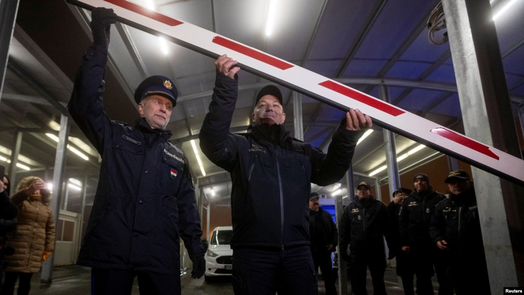 Romanian Chief Border Inspector Stoica Laurian Cornel and Janos Balogh, the director-general of the Hungarian Police, lift a barrier as Romania and Bulgaria both join the visa-free Schengen zone on January 1.