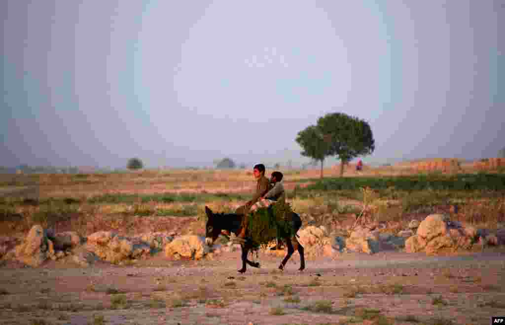 Afghan children ride a donkey along a track on the outskirts of Mazar-e Sharif. (AFP/Farshad Usyan)