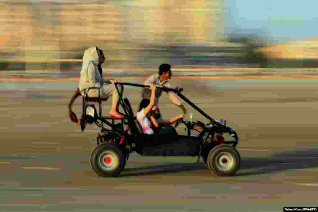 People ride a buggy on a beach in Karachi, Pakistan. (epa-EFE/Rehan Khan)