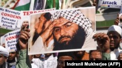Indian Muslims hold a scratched photo of Jaish-e Mohammad group chief, Maulana Masood Azhar, as they shout slogans against Pakistan during a protest in Mumbai on February 15.