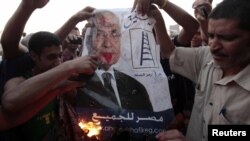 Protesters burn a defaced poster of presidential candidate Ahmed Shafiq, ousted leader Hosni Mubarak's last prime minister, at Cairo's Tahrir Square on June 14.