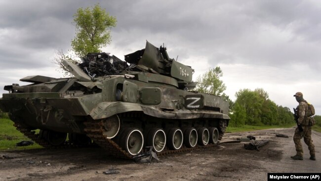 A Ukrainian serviceman walks past a destroyed Russian APC north of Kharkiv (file photo)