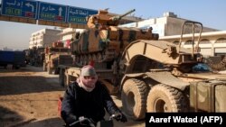 A Turkish military convoy of tanks and armored vehicles passes through the Syrian town of Dana, east of the Turkish-Syrian border in the northwestern Idlib Province, on February 2.