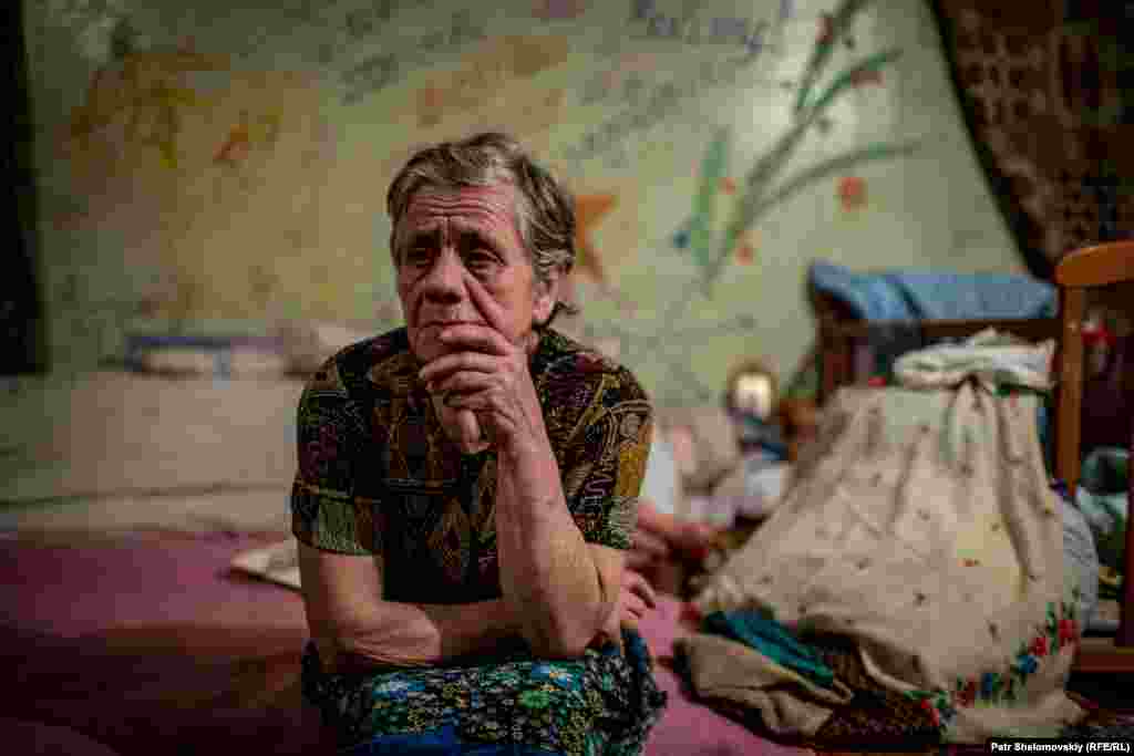 Maria, 75, sits on her bed in the shelter.