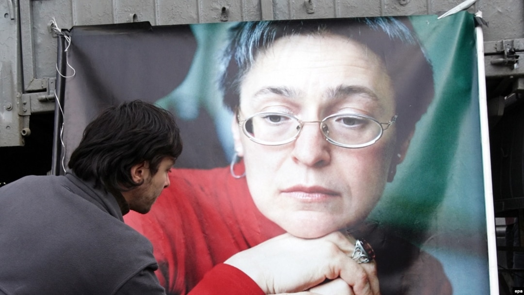 A Russian man lays flowers near the picture of murdered journalist Anna Politkovskaya during a rally in Moscow on the anniversary of her death in 2009.