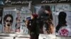 A Taliban fighter walks past a beauty salon with images of women defaced using spray paint in the Shar-e Naw neighborhood in Kabul.