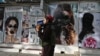 Боевик «Талибана» проходит мимо кабульского салона красоты с изображениями, закрашенными аэрозольной краской 
