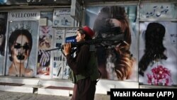 Боевик «Талибана» проходит мимо кабульского салона красоты с изображениями, закрашенными аэрозольной краской 