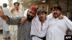 Pakistan - Pakistani shopkeepers help an injured victim following a bomb blast in Peshawar, 28May2009