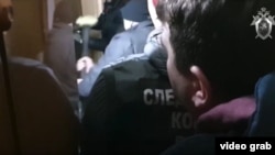 A video posted on YouTube by the Investigative Committee showed its officers along with those of the FSB using a sledgehammer to break down the door of what appeared to be an apartment.