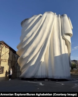 Sculptor Armen Samvelian with a section of the aluminum statue at an open-air workshop in Zovuni