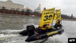 Greenpeace activists hold flags reading "Free the Arctic 30" as they go past the Kremlin by boat.