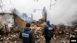 Наблюдатели ОБСЕ осматривают здание, разрушенное в ходе обстрелов в Авдеевке в феврале этого года