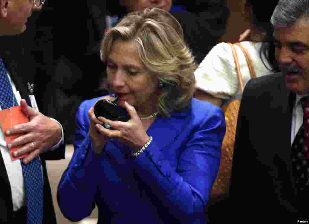 U.S. Secretary of State Hillary Clinton pauses to put on lipstick while talking with Turkish President Abdullah Gul (right) at the start of a United Nations Security Council meeting at the UN headquarters in New York on September 23, 2010.