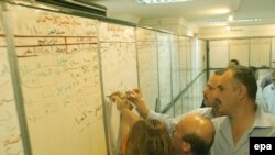 Stockbrokers write prices on a board at the Iraqi Stock Exchange