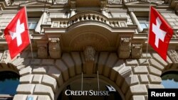 Switzerland - Switzerland's national flags fly beside the logo of Swiss bank Credit Suisse in Zurich, April 24, 2017.