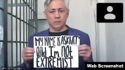 Асхат Жексебаев на онлайн-суде держит плакат, на котором на английском языке написано: «Меня зовут Асхат, и я не экстремист». Алматы, 28 сентября 2021 года