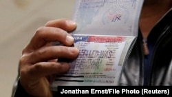 A member of the Al-Murisi family, Yemeni nationals who were denied entry into the United States because of a recent travel ban, shows the canceled visa in a passport from their failed attempt to enter the country. (file photo)