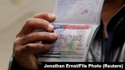 A member of the Al-Murisi family, Yemeni nationals who were denied entry into the United States because of a recent travel ban, shows the cancelled visa in their passport from their failed attempt to enter the country. (file photo)