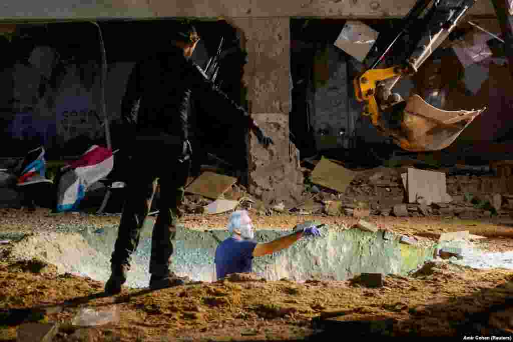 Israeli emergency workers inspect the impact crater of an Iranian rocket after it hit a school building in the center of the country.&nbsp;