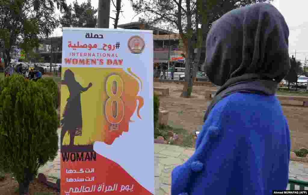 زن عراقی در حال خواندن پوستری به&zwnj;مناسبت روز زن در موصل