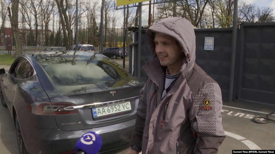 Ukrainian taxi driver Anatoliy Trepak stands next to his recently purchased Tesla in Kyiv.