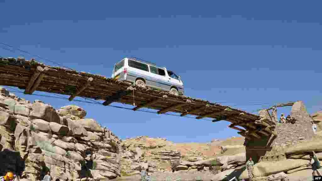 A vehicle drives over a wooden bridge in the province of Daykundi, Afghanistan. AFP PHOTO/Aref Yaqubi