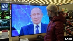 Жінка дивиться по телевізору в одному з кримських торгових центрів пресконференцію президента Росії Володимира Путіна, 17 грудня 2020 року. Ілюстративне фото
