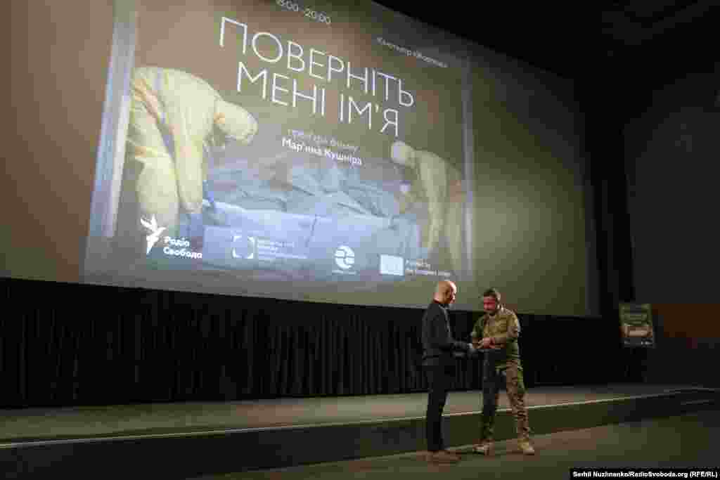 Бригадний генерал, заступник головнокомандувача Збройних сил України Андрій Лебеденко вручає почесний нагрудний знак «За сприяння війську» воєнкору Радіо Свобода та автору фільму Мар’яну Кушніру