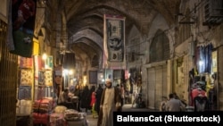 ISFAHAN, IRAN - AUGUST 20, 2018: A clergyman passing under a towel designed like a U.S. dollar bill. File photo