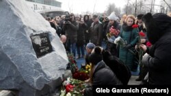 People lay flowers during a foundation stone laying ceremony for a future memorial site to the people killed in a plane shot down in Iran in January, at the Boryspil International Airport outside Kyiv, February, 17, 2020