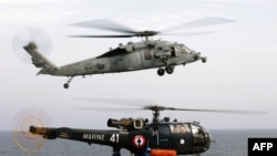 An US Navy MH-60 R/S Seahawk helicopter flies over a French Navy Alouette III as it lands on the flight deck of the French Navy aicraft carrier Charles de Gaulle in the Gulf of Oman. File photo