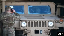 Украінскі вайсковец здымае прэзыдэнта Пятра Парашэнку, які сядзіць у браняваным аўтамабілі. Падчас цырымоніі сустрэчы першага амэрыканскага самалёта зь нелетальнай дапамогай. Кіеў, 25 сакавіка 2015 