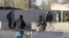 Afghan security forces stand guard on December 9 at the entrance gate of the airport near Kandahar that was stormed by the Taliban.