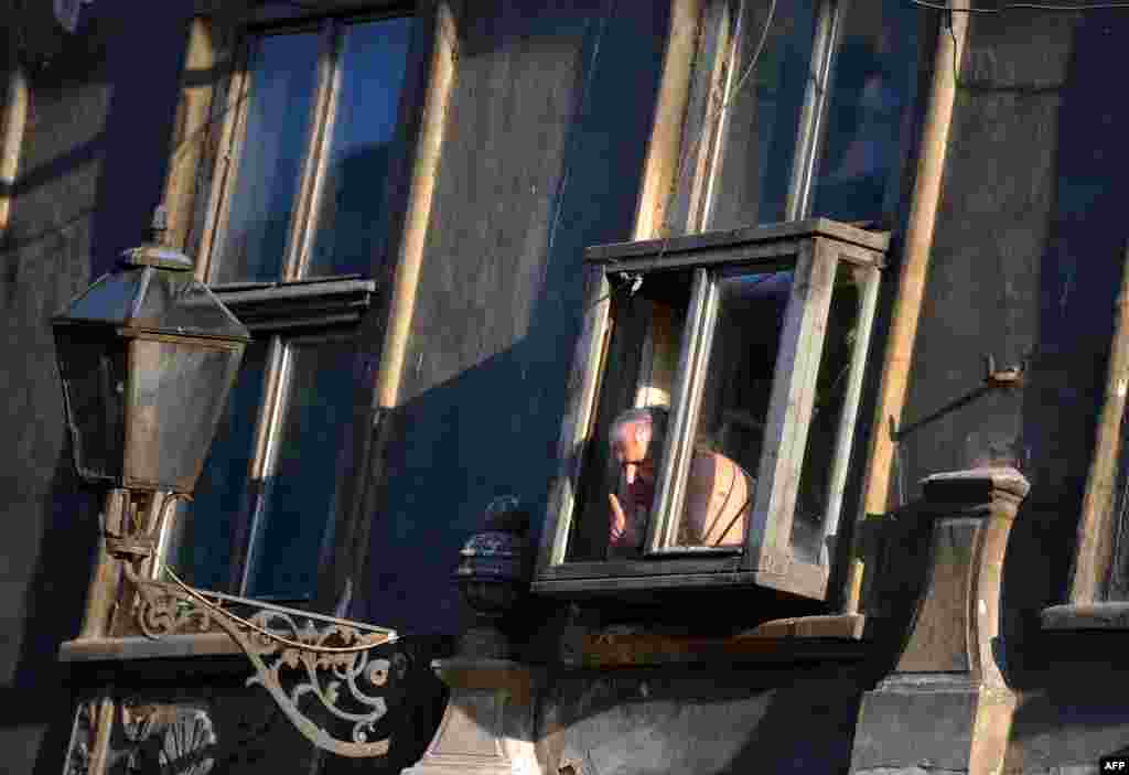 An elderly Serbian man looks down at the street as revellers pass during the annual EXIT music festival in the northern city of Novi Sad. (AFP/Andrej Isakovic)